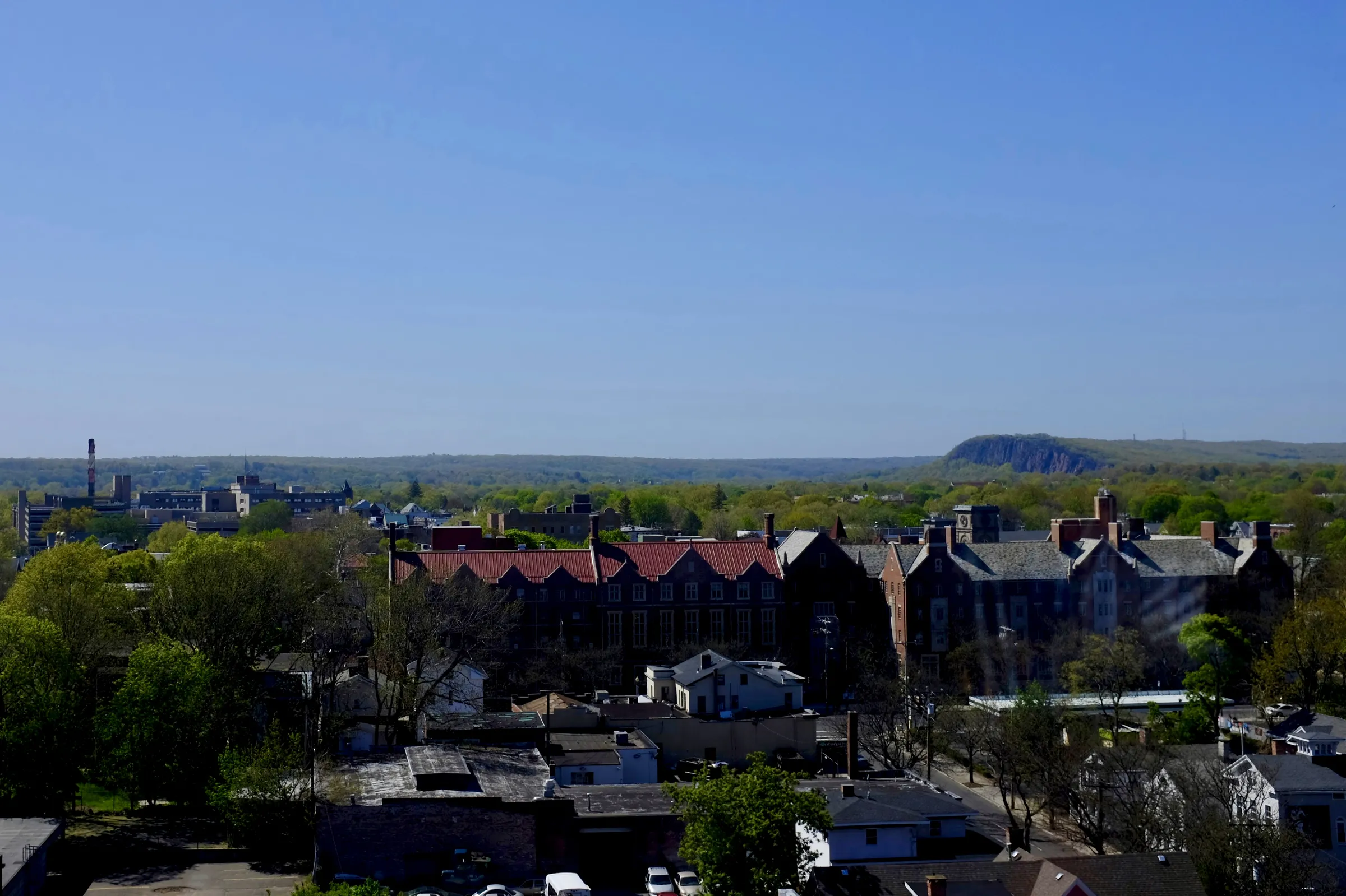 A northwest view from an apartment tower in New Haven, Connecticut. In the distance, beyond the city, the edge of a large, green hill.