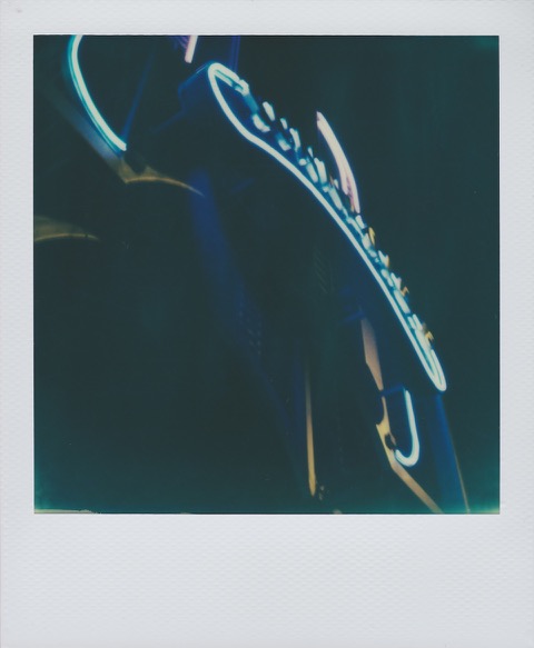 A color Polaroid photograph of the neon, art deco Sunnyside sign, lit at night, on 46th Street south of Queens Boulevard. Photo taken in Queens, New York City, USA.