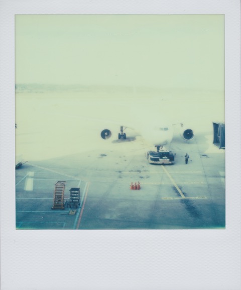 A color Polaroid photograph an airplane, preparing for boarding, sitting on the asphalt at the airport. Photo taken in Seoul, South Korea.
