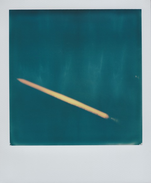 A color Polaroid photograph of a yellow wooden pencil on a desk. Photo taken in Queens, New York City, USA.