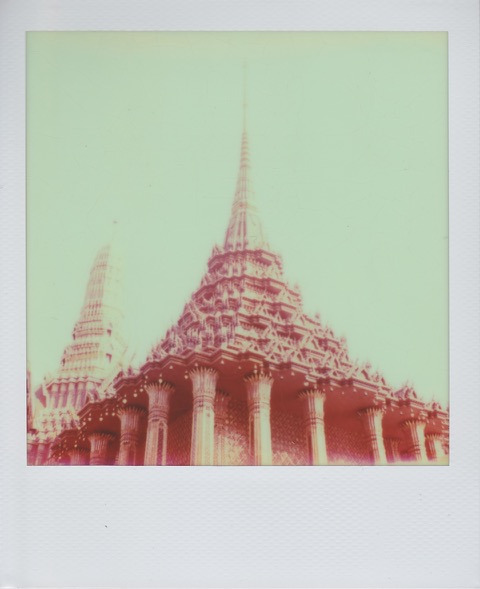 A color Polaroid photograph of a Thai temple, a large golden spire on top. Photo taken in Bangkok, Thailand.